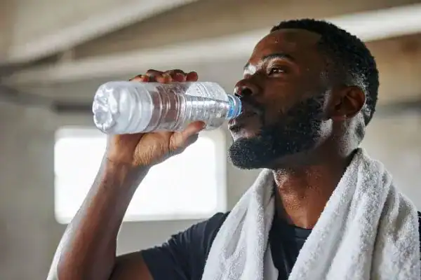 Image of man drinking water to improve hydration Chester after work out.